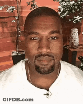 A Close Up Of A Man With A Beard Wearing A White Shirt And A Necklace . GIF