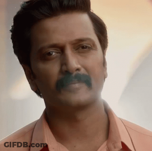 A Close Up Of A Man With A Mustache Wearing A Pink Shirt GIF