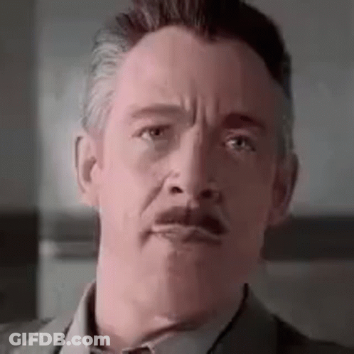 A Close Up Of A Man With A Mustache Wearing A Suit And Tie . GIF