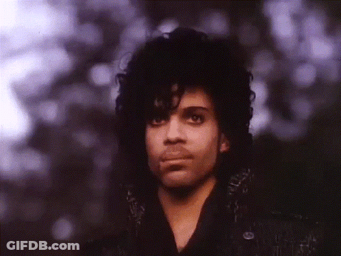 A Close Up Of A Man With Curly Hair And Purple Eyes GIF