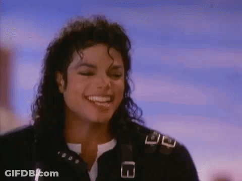 A Close Up Of A Man With Curly Hair Smiling In Front Of A Blue Sky . GIF