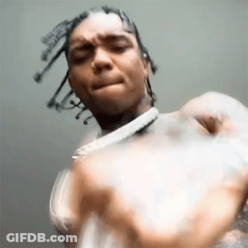A Close Up Of A Man With Dreadlocks And A Necklace Making A Face . GIF