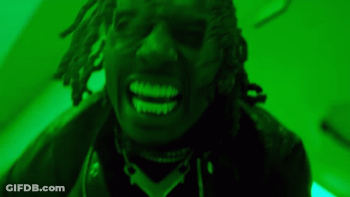 A Close Up Of A Man With Dreadlocks Smiling In A Green Room . GIF
