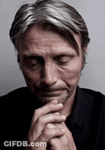 A Close Up Of A Man With His Eyes Closed And His Hands Folded GIF