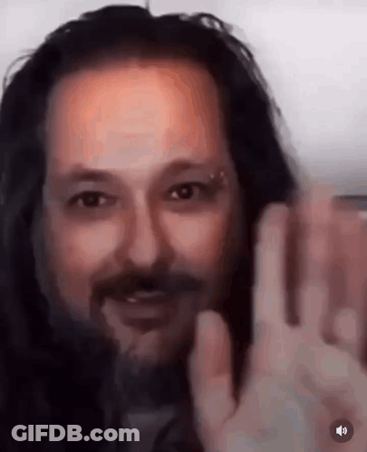 A Close Up Of A Man With Long Hair And A Beard Waving At The Camera . GIF