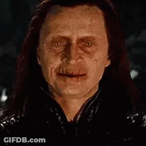 A Close Up Of A Man With Long Hair And A Scary Face Smiling At The Camera . GIF