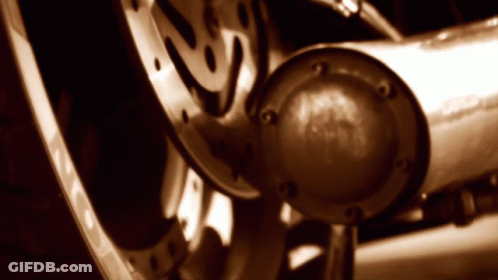 A Close Up Of A Motorcycle Wheel With A Exhaust Pipe In The Foreground GIF