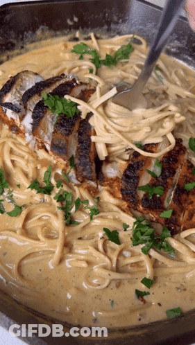 A Close Up Of A Pan Of Pasta With Chicken And Parsley GIF