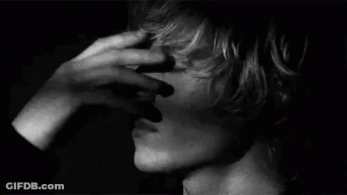 A Close Up Of A Person Covering Their Face With Their Hand . GIF