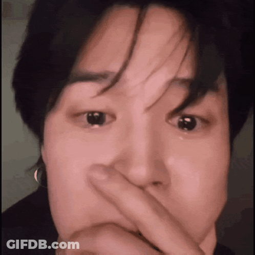 A Close Up Of A Person Covering Their Mouth With Their Finger . GIF