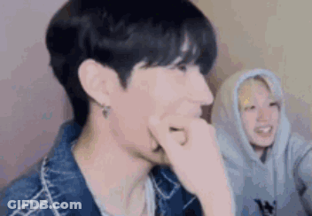 A Close Up Of A Person Covering Their Mouth With Their Hand While Another Person Looks On . GIF