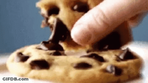 A Close Up Of A Person Eating A Chocolate Chip Cookie With Their Finger . GIF