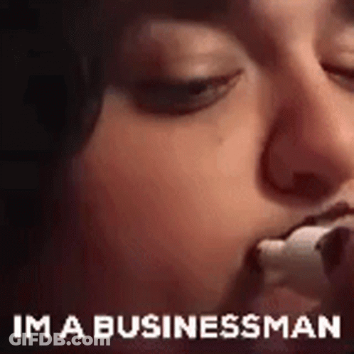 A Close Up Of A Person Eating A Marshmallow With The Words `` Im A Businessman '' Written Below It . GIF