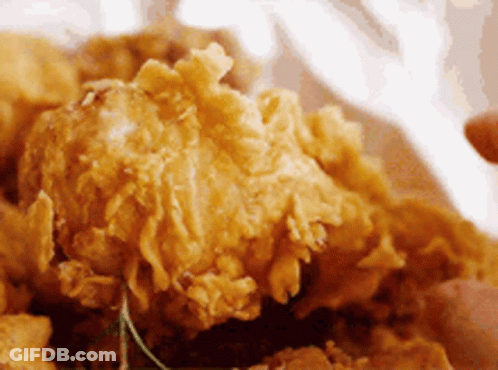 A Close Up Of A Person Eating Fried Chicken GIF