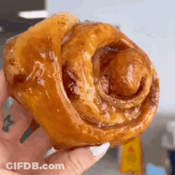 A Close Up Of A Person Holding A Cinnamon Roll . GIF
