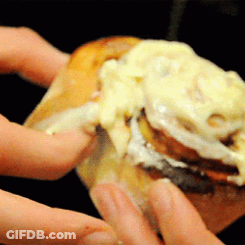 A Close Up Of A Person Holding A Cinnamon Roll With Cream Cheese GIF