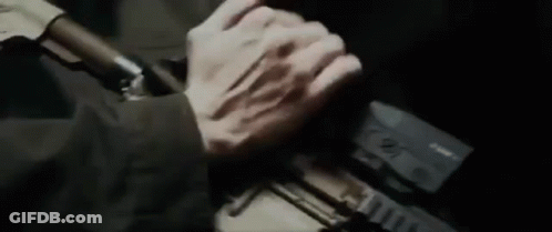 A Close Up Of A Person Holding A Gun With Their Hands . GIF