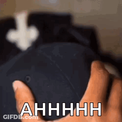 A Close Up Of A Person Holding A Hat That Says " Ahhhh " On It GIF