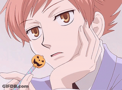 A Close Up Of A Person Holding A Lollipop With A Face On It GIF
