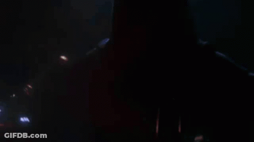 A Close Up Of A Person Holding A Red Lightsaber In A Dark Room . GIF