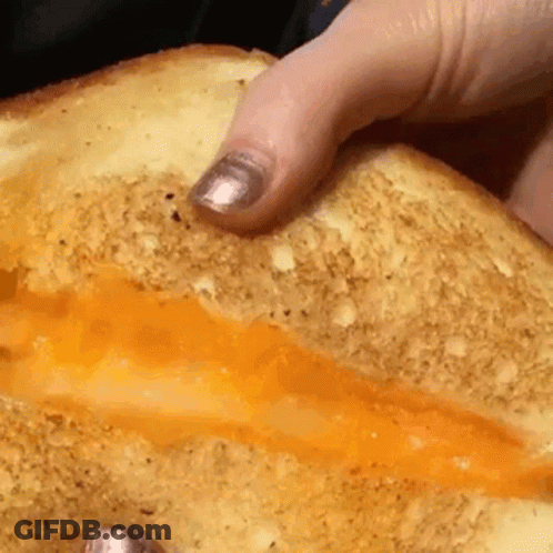 A Close Up Of A Person Holding A Sandwich With Cheese On It GIF