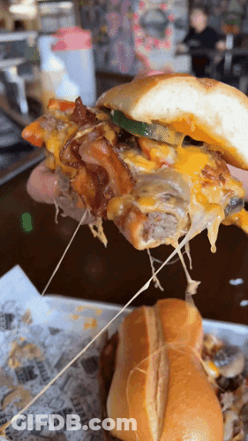 A Close Up Of A Person Holding A Sandwich With Cheese Pulled Out Of It GIF