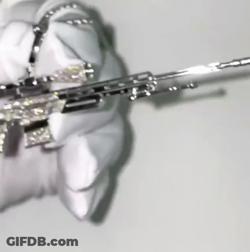 A Close Up Of A Person Holding A Silver Gun With Diamonds On It . GIF