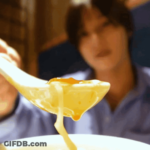 A Close Up Of A Person Holding A Spoon Full Of Soup GIF
