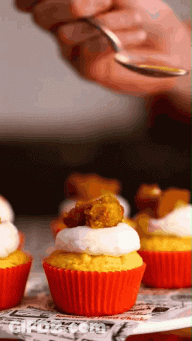 A Close Up Of A Person Holding A Spoon Over A Cupcake That Says Chicken On It GIF