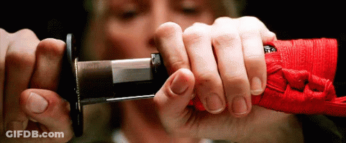 A Close Up Of A Person Holding A Sword With A Red Ribbon Around It GIF