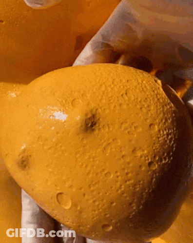 A Close Up Of A Person Holding A Yellow Potato With Water Drops On It GIF
