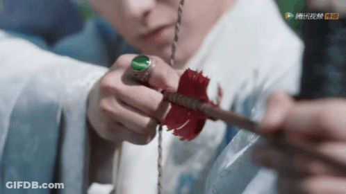 A Close Up Of A Person Holding An Arrow With A Green Ring GIF