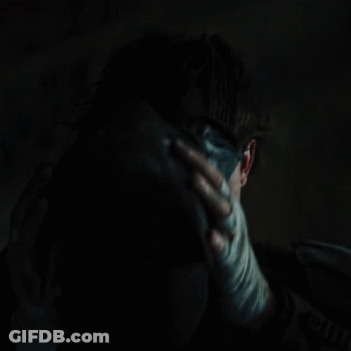 A Close Up Of A Person Holding Another Person 'S Face In A Dark Room GIF
