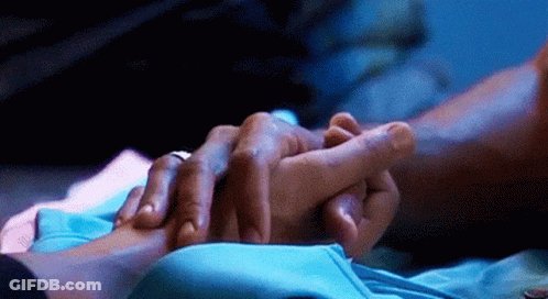 A Close Up Of A Person Holding Another Person 'S Hand In A Dark Room . GIF