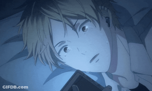 A Close Up Of A Person Laying In Bed Looking At A Cell Phone GIF
