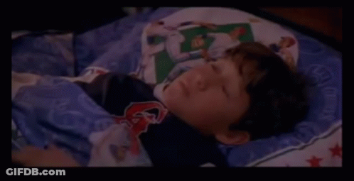 A Close Up Of A Person Laying On A Bed With A Blanket On It . GIF