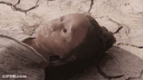 A Close Up Of A Person Laying On The Ground With Their Face Covered In Dirt GIF