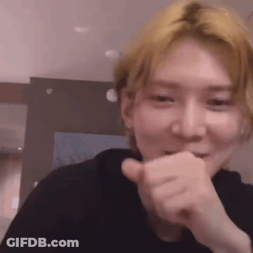 A Close Up Of A Person Making A Funny Face While Covering Their Mouth With Their Hand . GIF