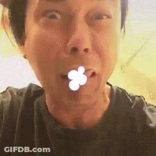 A Close Up Of A Person Making A Funny Face With A Flower In Their Mouth . GIF
