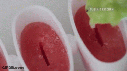 A Close Up Of A Person Making Ice Cream Popsicles With A Green Leaf . GIF