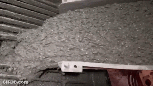 A Close Up Of A Person Pouring Concrete Into A Container . GIF