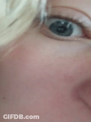 A Close Up Of A Person 'S Blue Eye With A Reflection Of A Person 'S Face . GIF