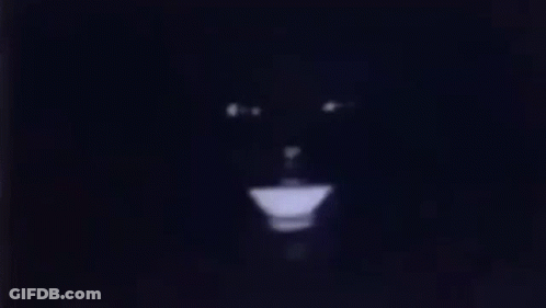 A Close Up Of A Person 'S Face In The Dark With A Light Coming Out Of It . GIF