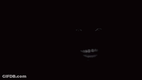 A Close Up Of A Person 'S Face In The Dark With A Smile On It . GIF