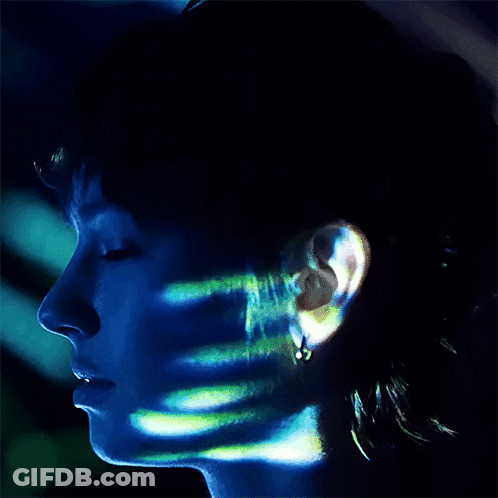 A Close Up Of A Person 'S Face With A Blue Light Shining On It GIF