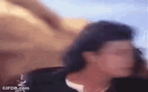 A Close Up Of A Person 'S Face With A Blurry Background And A Person In The Background . GIF