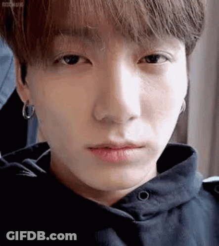 A Close Up Of A Person 'S Face With A Hoodie And Earrings . GIF