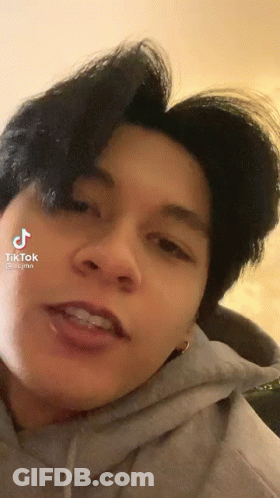 A Close Up Of A Person 'S Face With A Hoodie On And A Purple Haircut . GIF