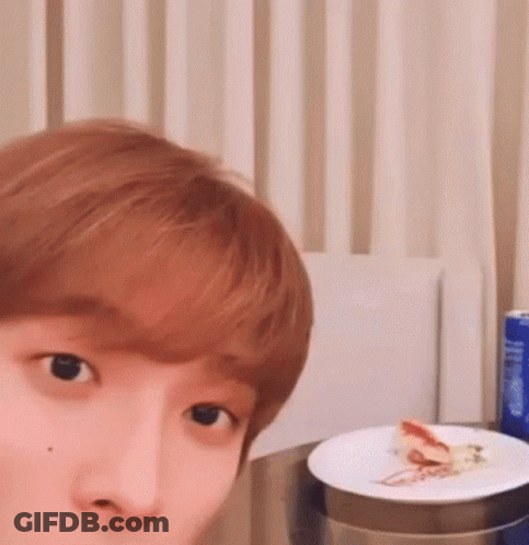 A Close Up Of A Person 'S Face With A Plate Of Food On A Table . GIF