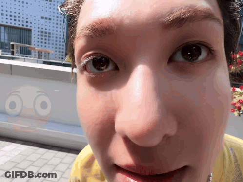 A Close Up Of A Person 'S Face With A Smiley Face Behind It GIF